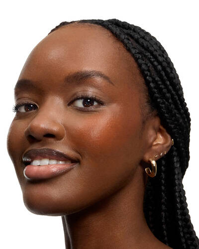 Smiling woman with long braids and glossy lips.