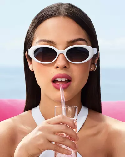 Olivia Rodrigo con occhiali da sole bianchi e un look con labbra malva.