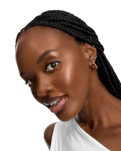 Donna sorridente con lunghe trecce e pelle luminosa.