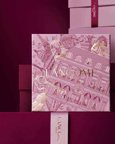 Immagine del cofanetto regalo Lancome Natale rosa davanti a una composizione di cofanetti rosa e rosso intenso, su sfondo rosso intenso.
