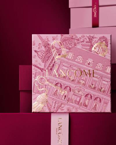 Immagine del cofanetto regalo Lancome Natale rosa davanti a una composizione di cofanetti rosa e rosso intenso, su sfondo rosso intenso.