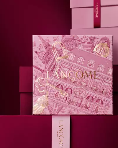Immagine del cofanetto regalo Lancome Natale rosa davanti a una composizione di cofanetti rosa e rosso intenso, su sfondo rosso intenso.