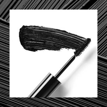 A close-up of a mascara wand with a bold black stroke of mascara against a white background.
