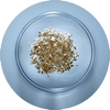 A small mound of light brown crystalline salt placed in the center of a clear glass dish, set against a blue background.