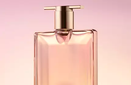 A sleek, elegant perfume bottle with a gold cap, set against a soft pink background.