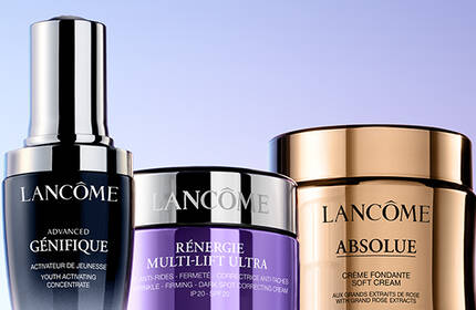 Three Lancome skincare products are displayed against a gradient background, showcasing their sleek packaging in purple and gold tones.
