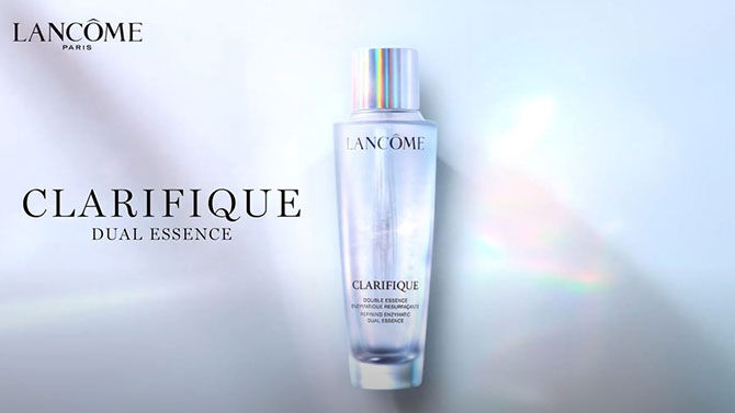 A sleek, translucent bottle of Lancome Clarifique Dual Essence against a light background, featuring the Lancome logo and product name prominently displayed.