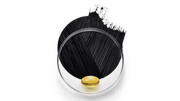 An image featuring a golden gel capsule placed on a transparent circular surface, accompanied by a bold stroke of black paint and a cluster of fine black lines in the background.