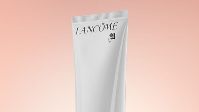 A tube of Lancome skincare product set against a soft pastel background.