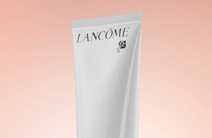 A tube of Lancome skincare product set against a soft pastel background.