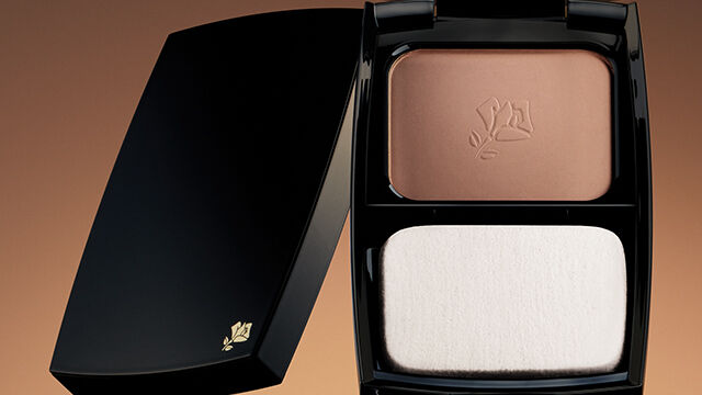 A compact powder case with two sections: one containing a bronzer shade and the other a lighter foundation shade, set against a warm gradient background.