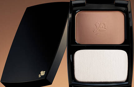 A compact powder case with two sections: one containing a bronzer shade and the other a lighter foundation shade, set against a warm gradient background.