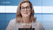A woman with blonde, wavy hair and large glasses is smiling at the camera, introducing herself as Annie Black. She is wearing a white lab coat, and the background features a blue and white grid pattern. Text on the screen includes her name.