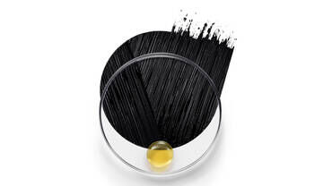 An artistic representation featuring a circular container with a glossy, yellow substance at the bottom, and a streak of black paint or ink flowing over the top.