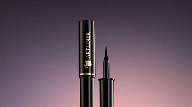 A sleek black mascara tube with a thin applicator wand, set against a gradient background.