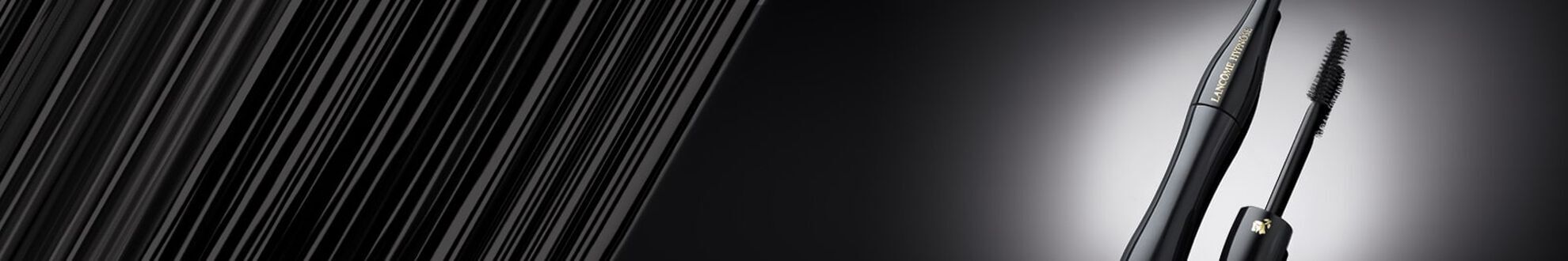 A close-up of a sleek black mascara tube next to a mascara wand, set against a gradient background that transitions from dark to light.