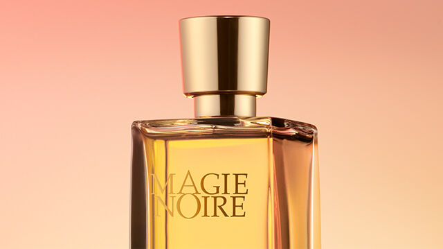 A close-up of a perfume bottle with a golden cap, set against a soft gradient background of warm colors.