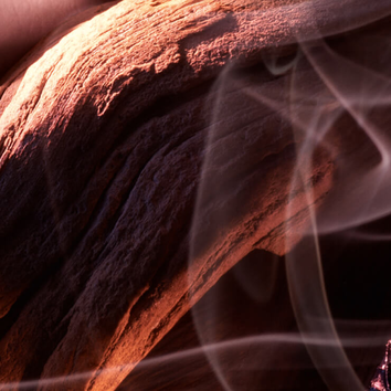 Tronco di legno con venature visibili e fumi evanescenti che danzano nell'aria, creando un'atmosfera mistica.