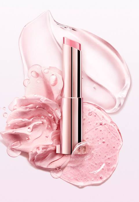 Un rossetto rosa elegante posizionato su uno sfondo di gocce di gel e petali di rosa.
