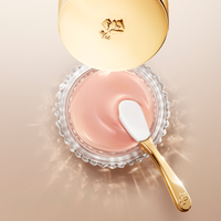 Vista dall'alto di un vasetto di crema Lancome Absolue l'Extrait con tappo e spatola dorati.
