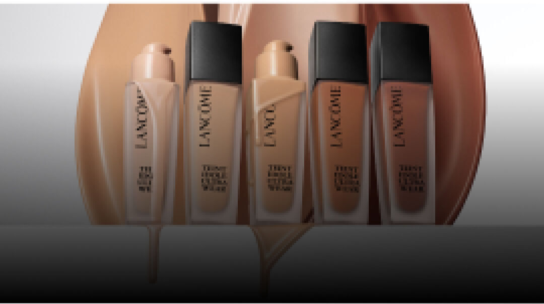Immagine che mostra diversi flaconi di fondotinta Lancome su uno sfondo sfumato.