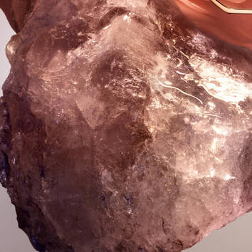 Un cristallo traslucido con sfumature rosa e arancioni su uno sfondo neutro, che mette in risalto la sua brillantezza.