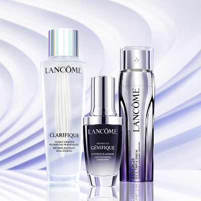 Tre prodotti per la pelle Lancome su sfondo viola chiaro ondulato.