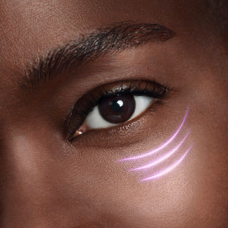Primo piano di un occhio con segni luminosi viola sulla guancia, evidenziando la pelle scura e i dettagli del viso.