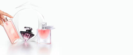 Tre flaconi di profumo elegantemente disposti su uno sfondo chiaro, con un flacone rosa chiaro in primo piano.