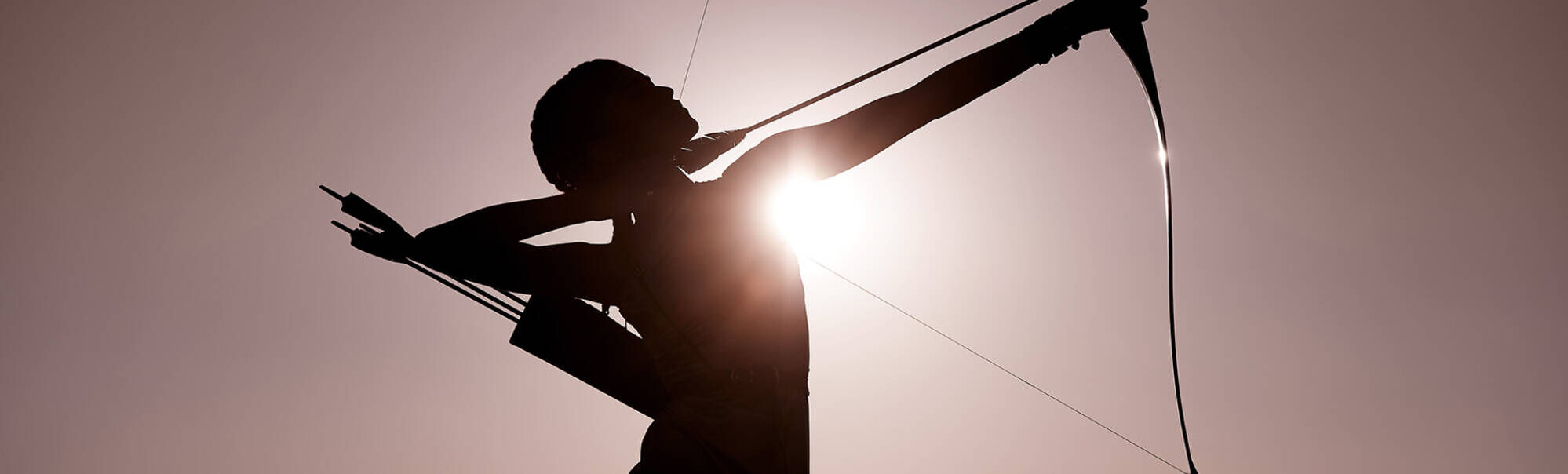 Silhouette di un arciere che tende una corda d'arco, con il sole che splende dietro di lui.