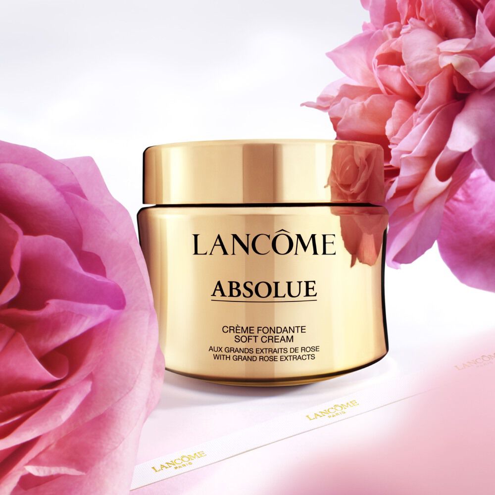 Un barattolo di crema lenitiva Lancome Absolue su uno sfondo di fiori rosa.