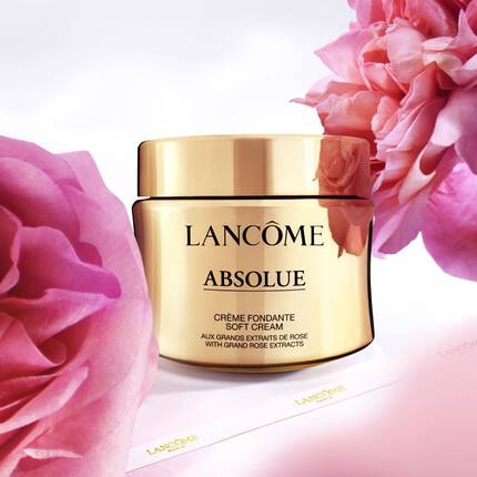 Un barattolo di crema lenitiva Lancome Absolue su uno sfondo di fiori rosa.
