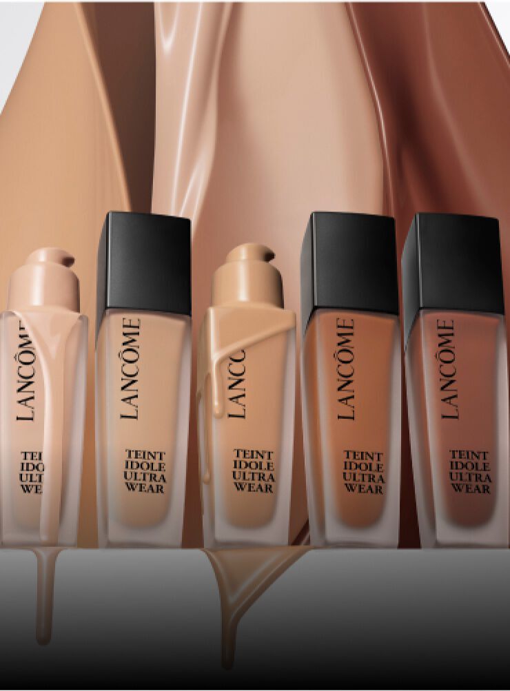 Immagine di tre flaconi di fondotinta Lancome Teint Idole Ultra Wear su uno sfondo di tonalita nude.