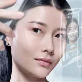 Una giovane donna guarda verso uno schermo digitale che mostra un'analisi della pelle, evidenziando parametri come la luminosita e le imperfezioni.