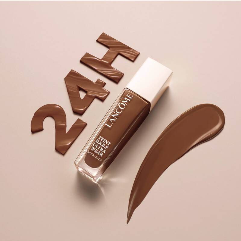 Immagine di un fondotinta Lancome con la scritta "24H" in marrone, accanto a una striscia di prodotto su uno sfondo beige.