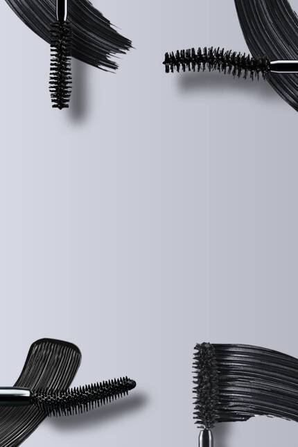 Immagine che mostra diversi applicatori di mascara e un prodotto cosmetico nero su sfondo grigio.