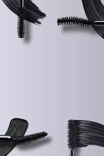 Immagine che mostra diversi applicatori di mascara e un prodotto cosmetico nero su sfondo grigio.
